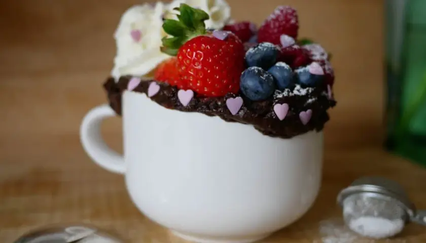 Chokladig mugcake med färska bär och vispgrädde, perfekt för ett snabbt mugcake recept.
