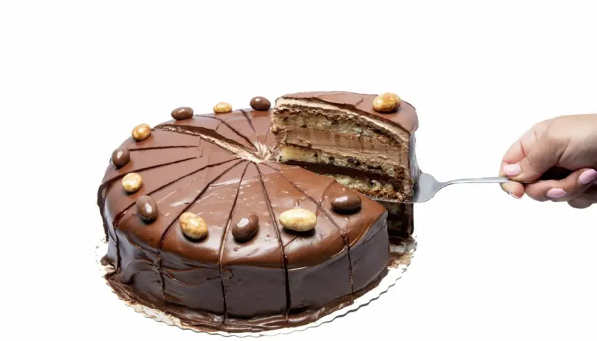 En chokladig nutellatårta med flera lager, en bit lyfts upp med en tårtspade. Perfekt för ett nutellatårta recept.