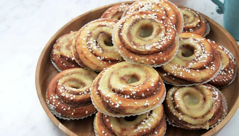 En hög med nybakade brioche bullar, glaserade och strösslade med pärlsocker, redo att avnjutas.