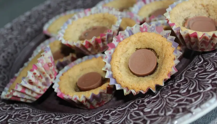 En skål med sega kakor, var och en med en chokladbit i mitten, i färgglada pappersformar.