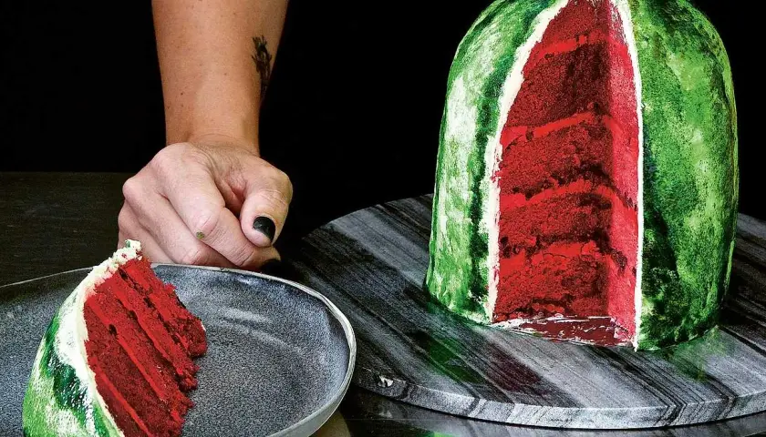 En skivad vattenmelon tårta med rött inre och grönt skal. En bit ligger på en tallrik.