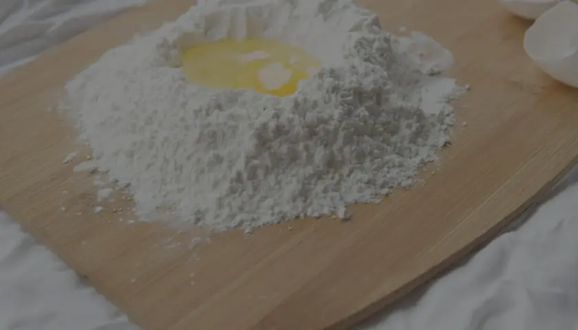 Mjöl och ett ägg på en skärbräda, redo att blandas. Kanske för en kaka där man använder bakpulver istället för jäst.