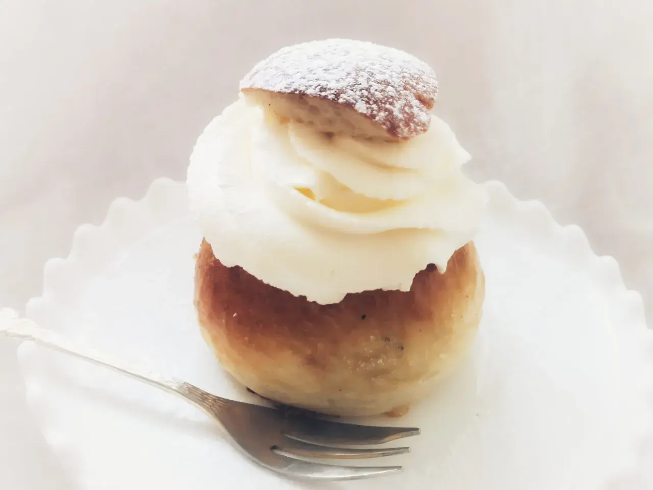 En semmeltårta med fluffig grädde och pudersocker, redo att avnjutas. Ett perfekt semmeltårta recept för fika.