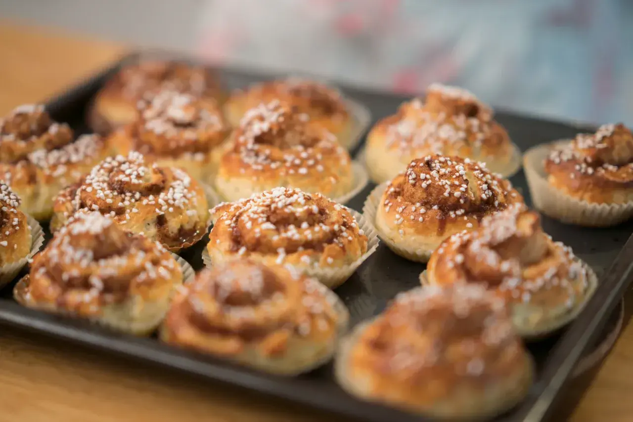 Nybakade glutenfria bullar med pärlsocker på en plåt, redo att avnjutas.