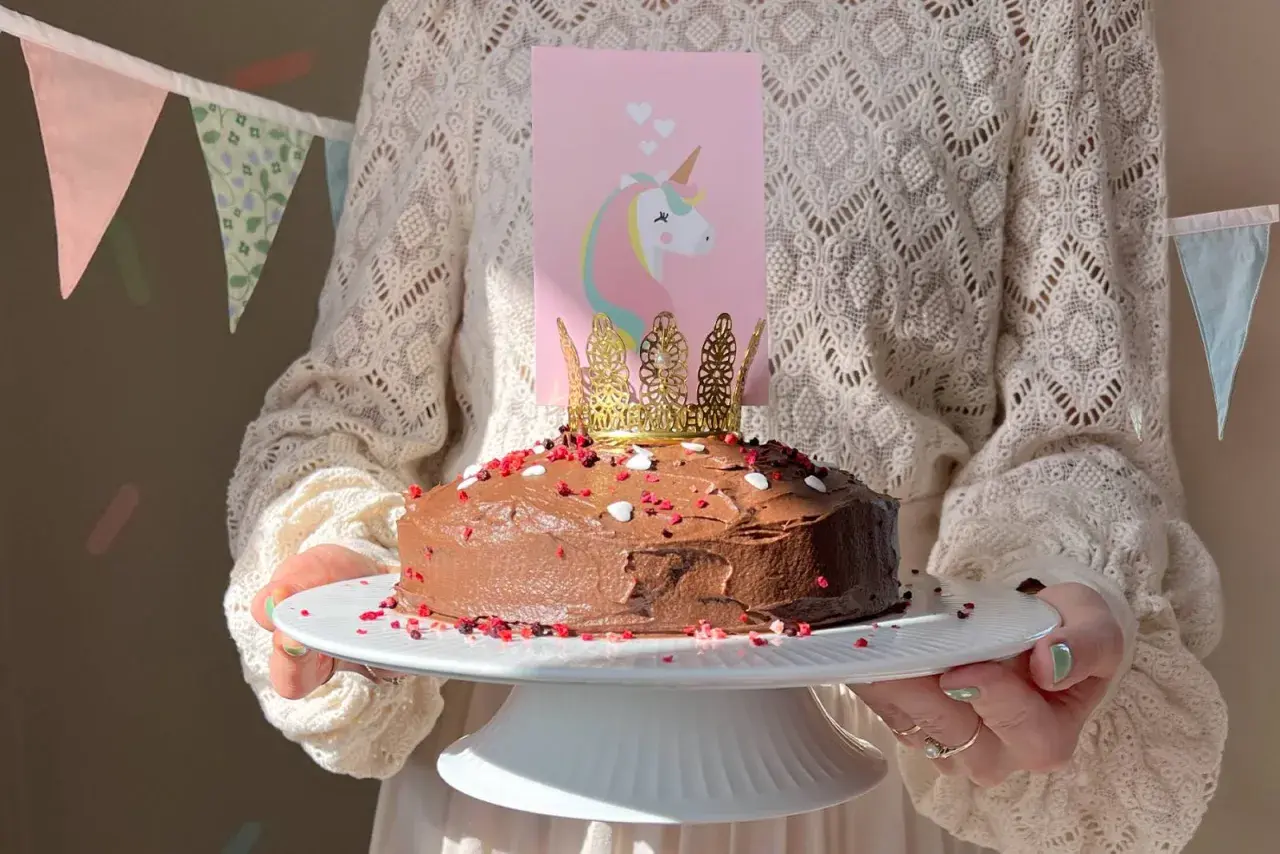 En chokladtårta med enhörningsdekoration och guldkrona, perfekt för roliga kakor barnkalas.