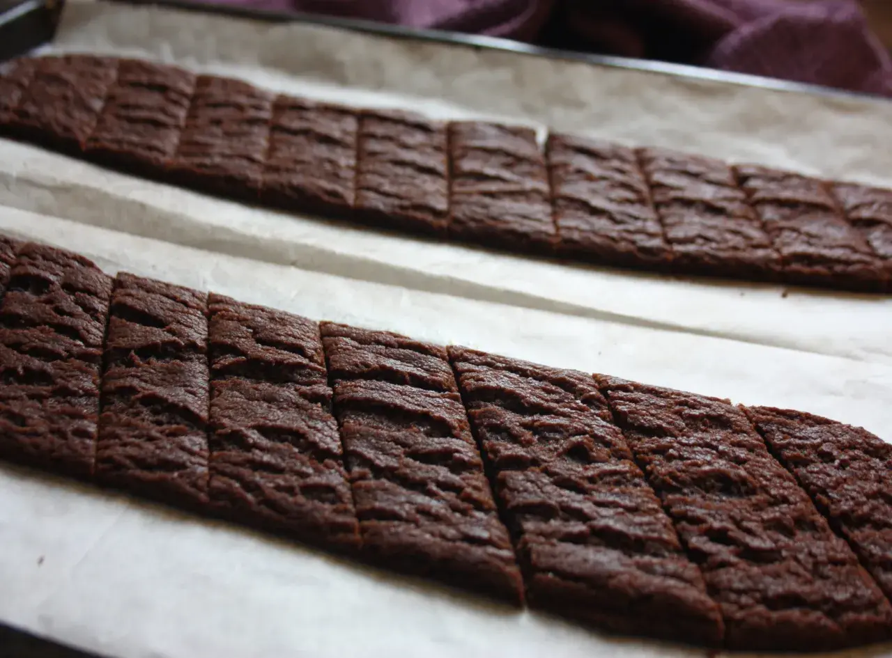 Två långa rader med nybakade chokladsnittar på bakplåtspapper. Perfekt för ett chokladsnittar recept.