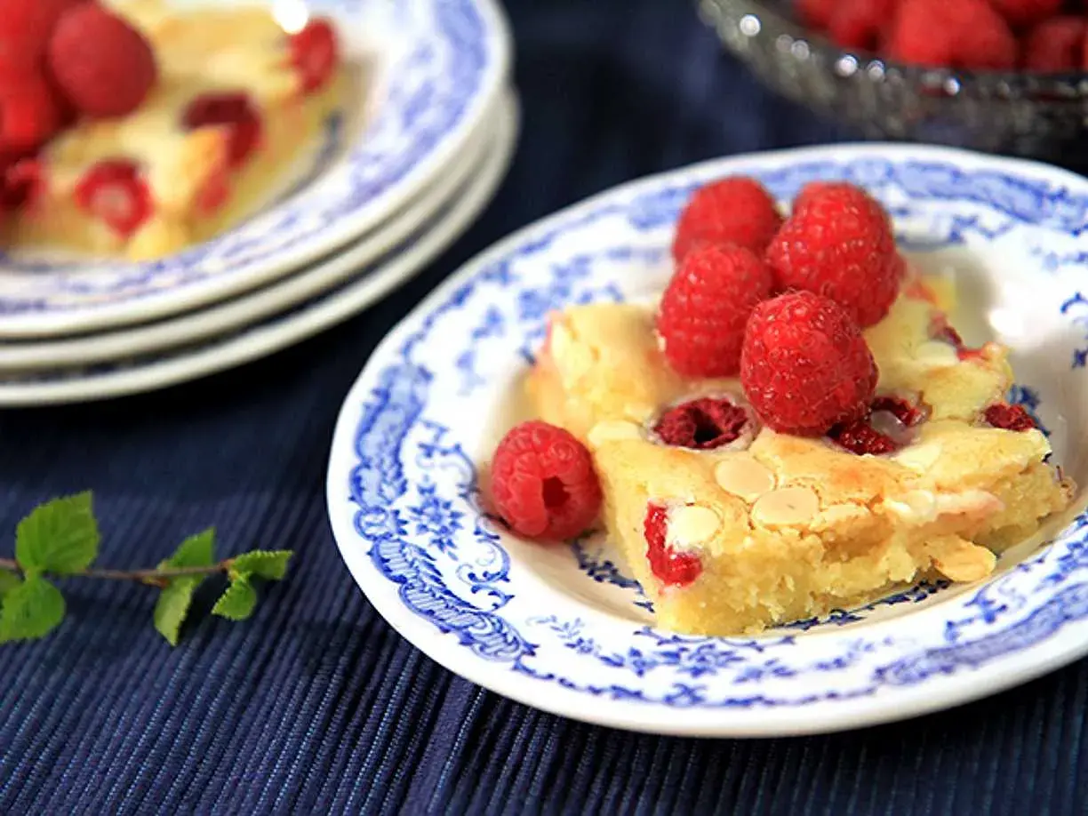 En bit hallonblondie på en blåvit tallrik, perfekt för ett somrigt blondie recept.