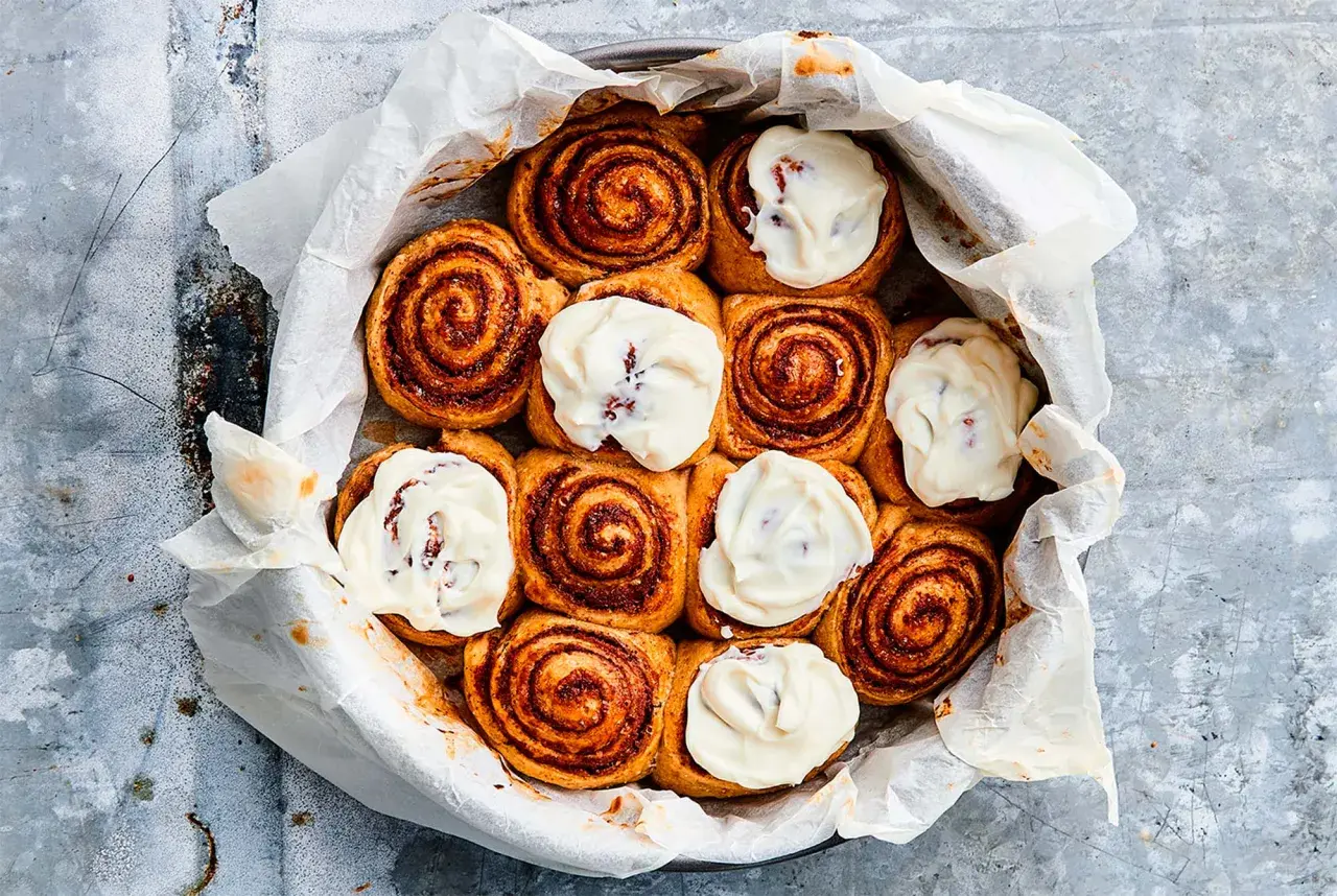 Kanelbullar med glasyr i en form, redo att frysa bulldeg för senare njutning.