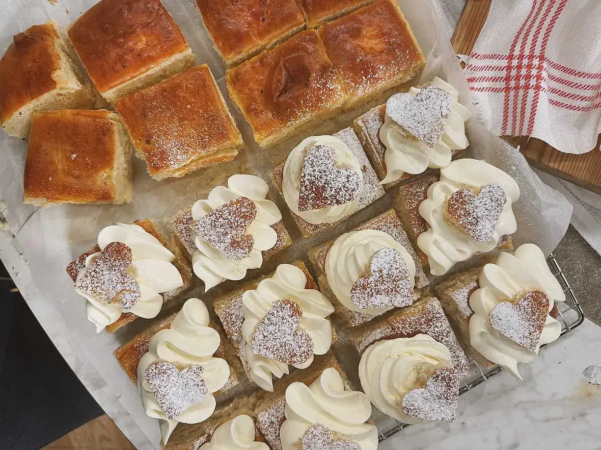 Fredriks fika: små fyrkantiga semlor med fluffig grädde och hjärtformade kakor, pudrade med florsocker. Perfekt för en mysig stund.
