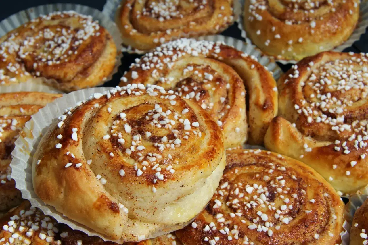 En tina med gyllene, nybakade kanelbullar toppade med pärlsocker. Perfekt för fika.
