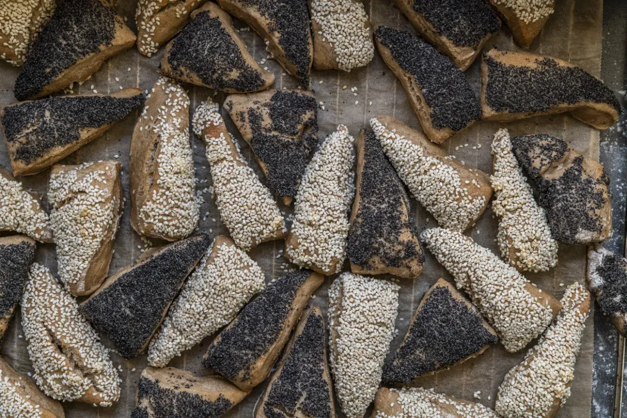 En hög med nybakade, trekantiga bröd med sesamfrön och vallmofrön. De ser ut som en härlig, gammal deg som väntar på att bli uppäten.