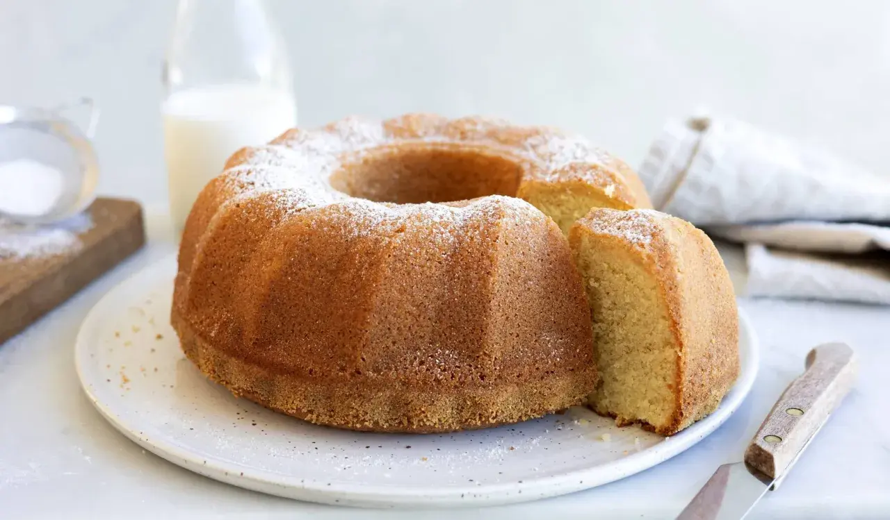 En gyllene sockerkaka med pudersocker, perfekt för ett enkelt sockerkaka recept. En bit är uppskuren.