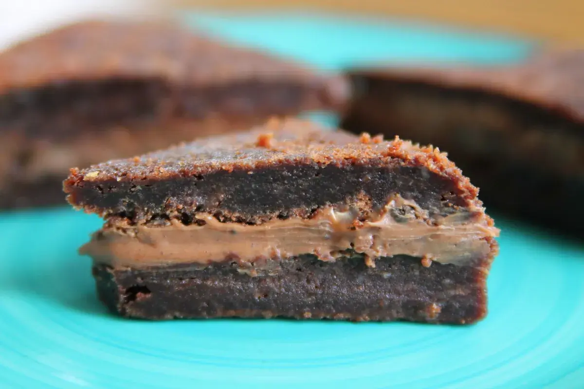 En bit chokladig kladdkaka med krämig fyllning, perfekt för en fika.