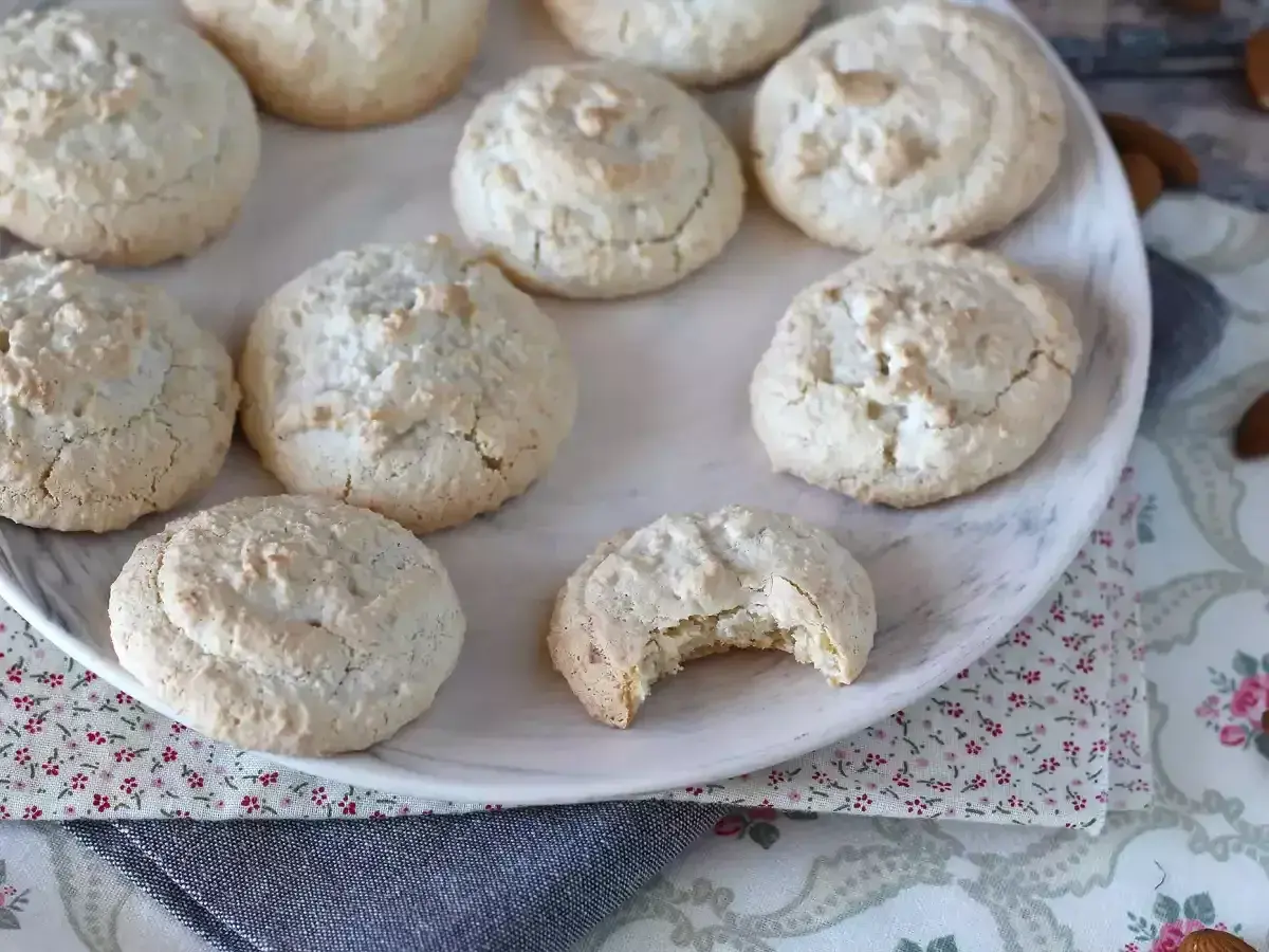 En tallrik med hembakade amaretti-kakor, perfekta för ditt nästa amaretti recept. En kaka är uppäten!