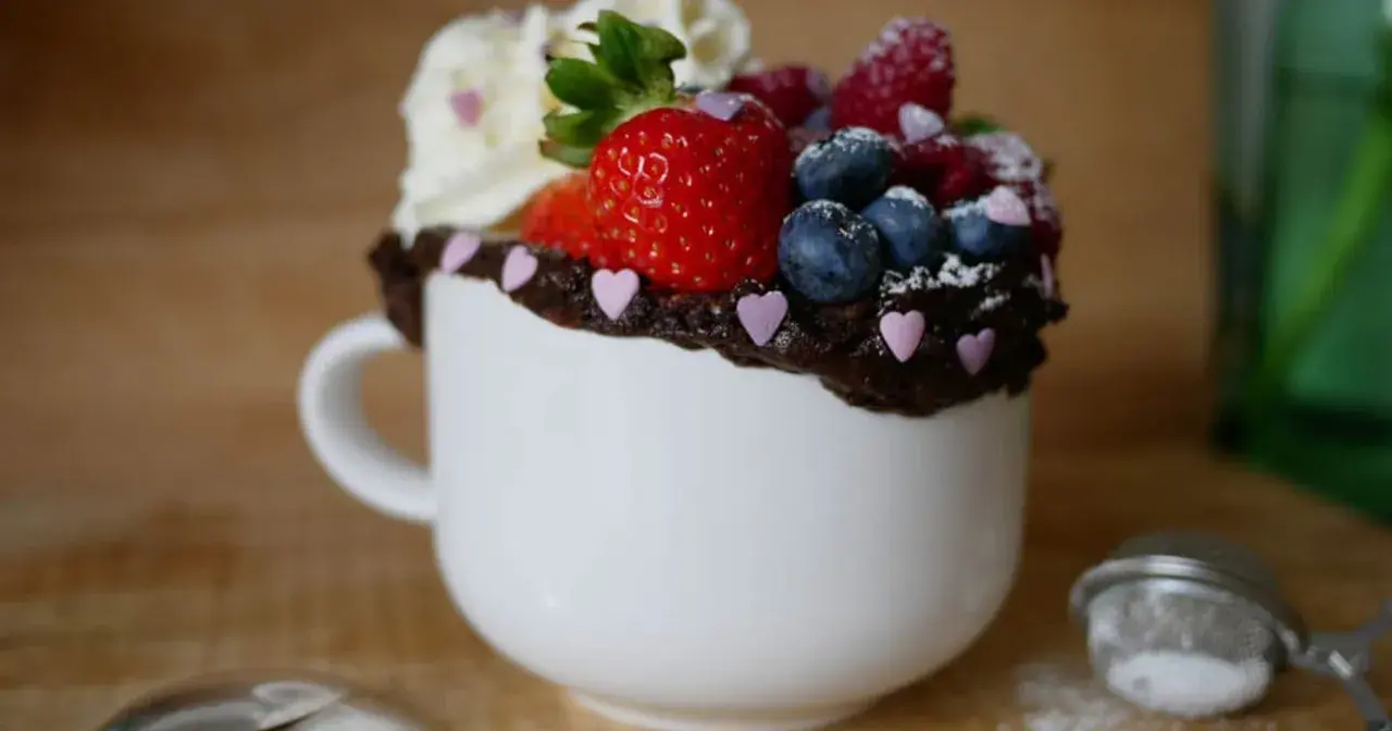 Chokladig mugcake med färska bär och vispgrädde, perfekt för ett snabbt mugcake recept.