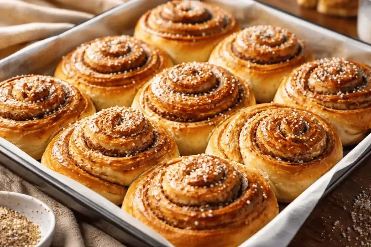 Nybakade kanelbullar i en form, gyllene och doftande. Denna kanelbulle deg har jäst till perfektion.