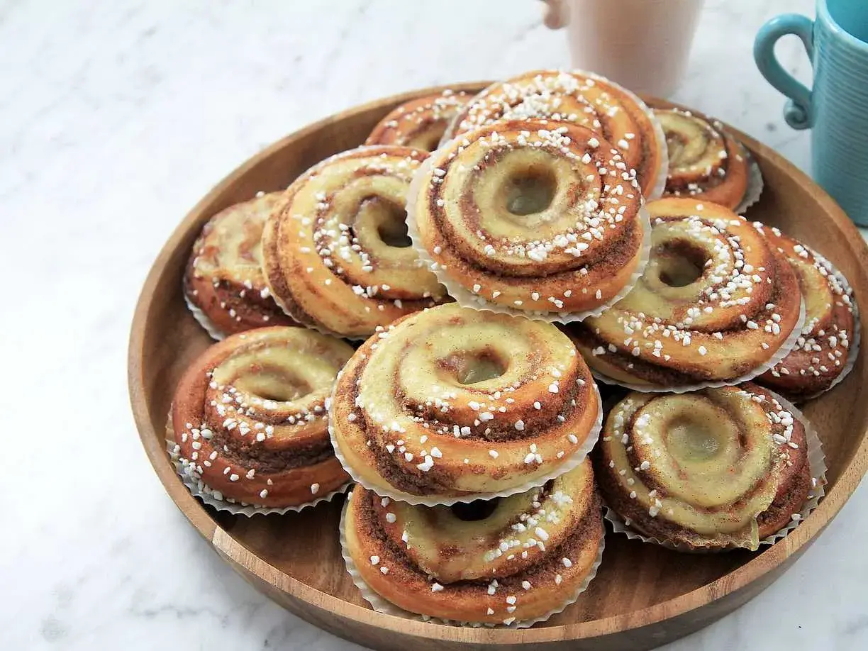 En hög med nybakade brioche bullar, glaserade och strösslade med pärlsocker, redo att avnjutas.