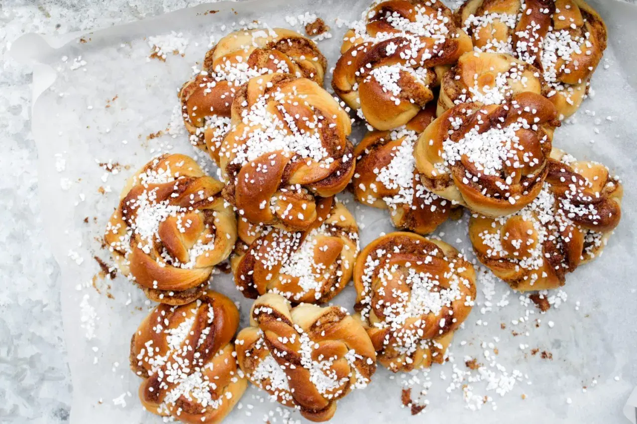 En hög med gyllene kanelbullar, toppade med pärlsocker. Perfekt för fikat, undrar vilken jäst till bullar som ger bäst resultat?