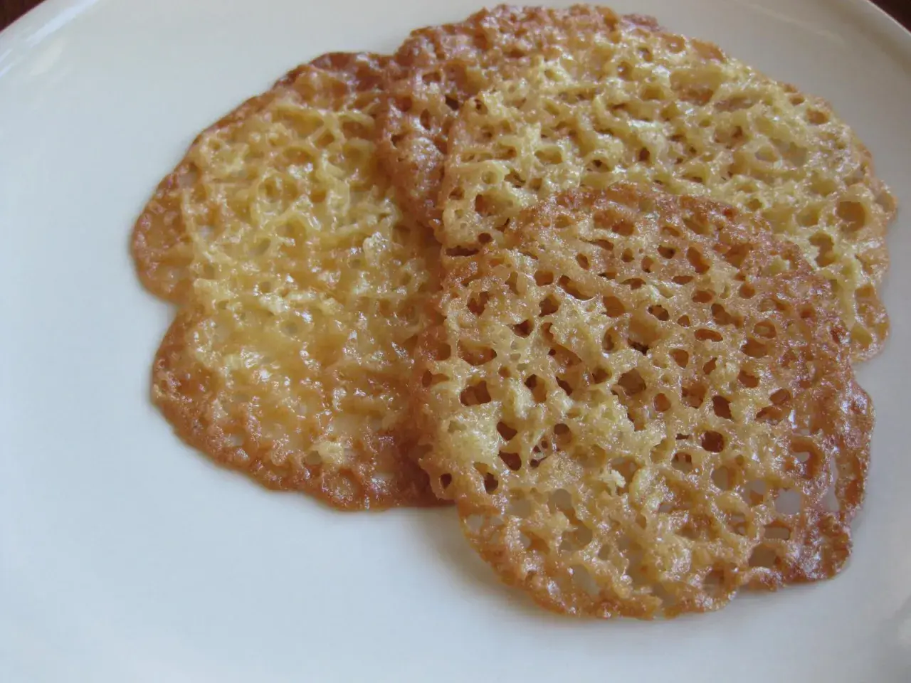 Tre gyllene, krispiga havreflarn ligger på en vit tallrik. Perfekta för ett enkelt recept på havreflarn.