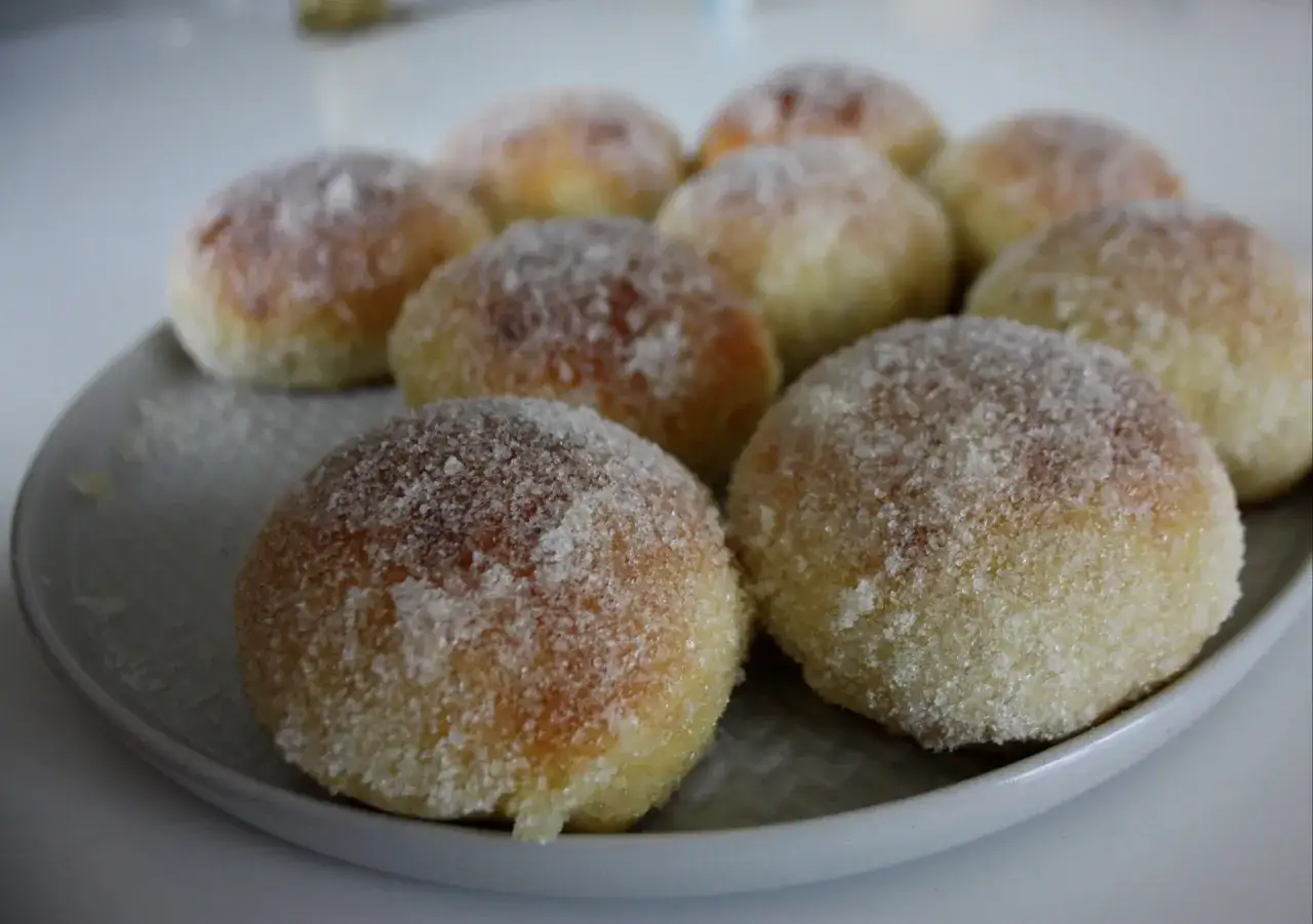 En tallrik med nybakade bullar, generöst täckta med strösocker på bullar. Perfekt för fikat!