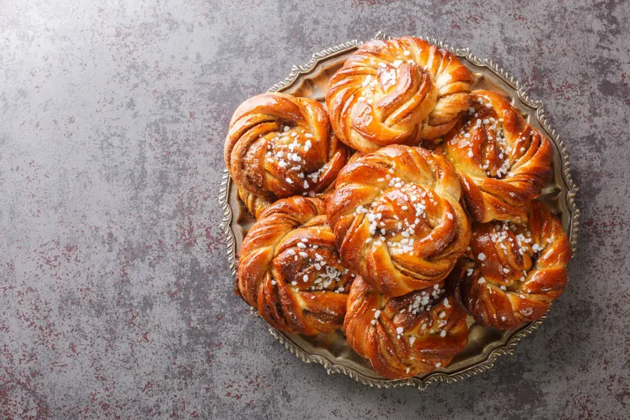 En bricka med gyllene, nybakade kanelbullar, strösslade med pärlsocker. Perfekt för fika!