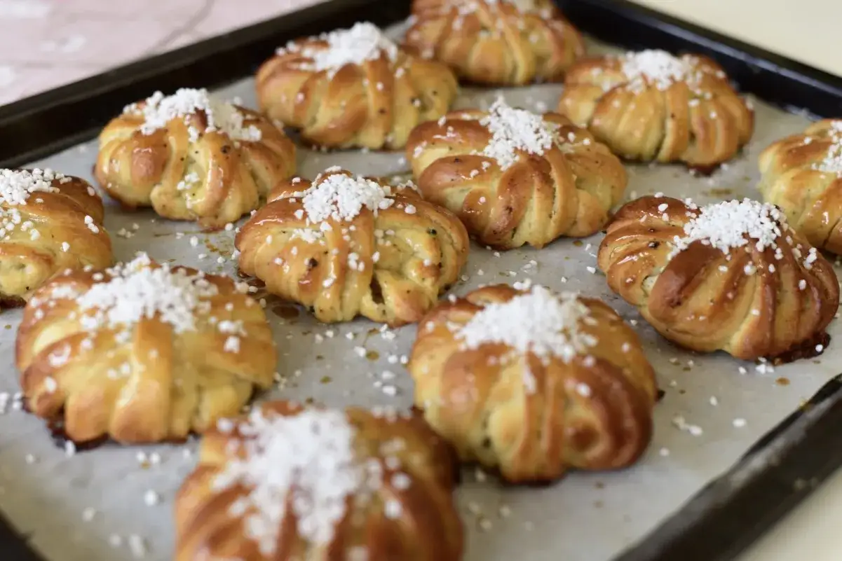 Nybakade bullar med mandelmassa och kardemumma, toppade med p&auml;rlsocker, ligger p&aring; en pl&aring;t.