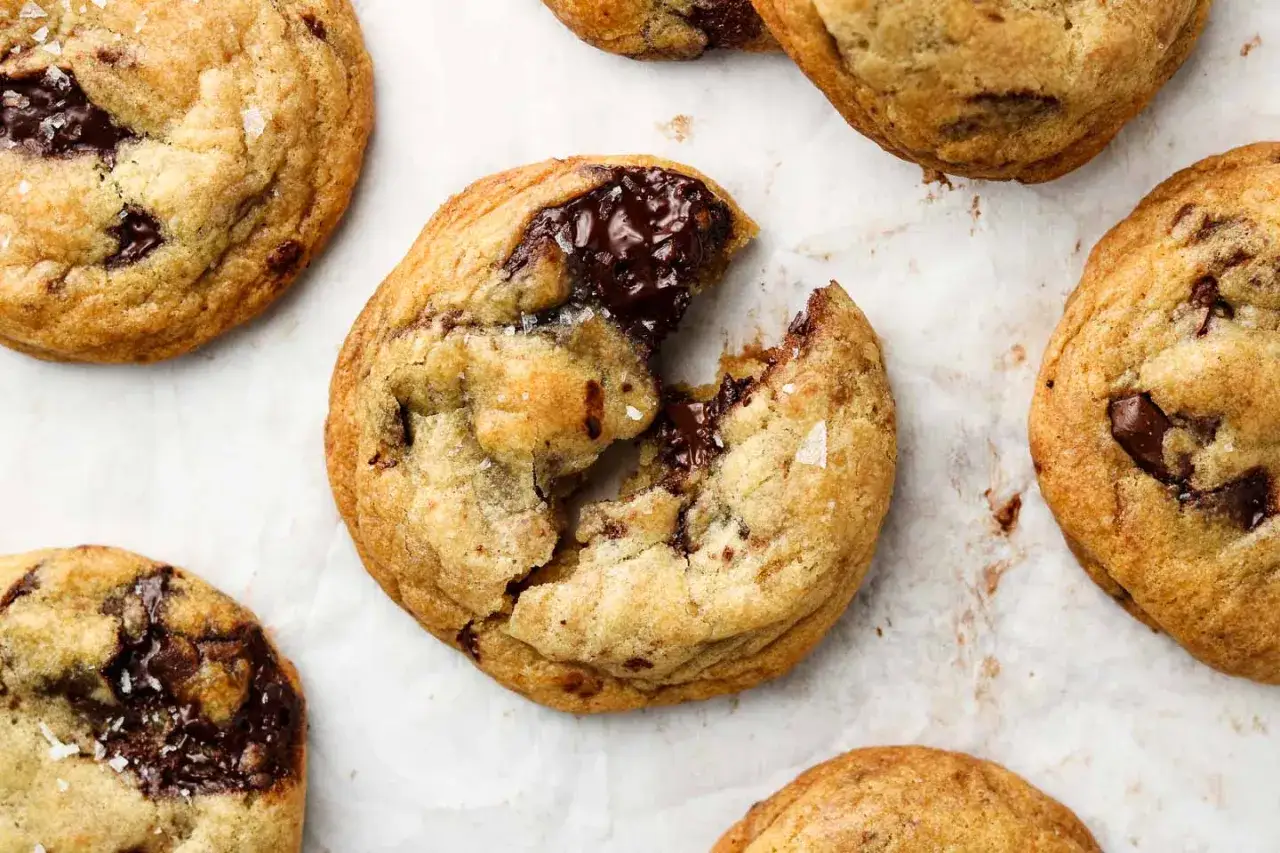 N&auml;rbild p&aring; flera veganska chocolate chip cookies, en &auml;r uppbruten och visar sm&auml;lt choklad.
