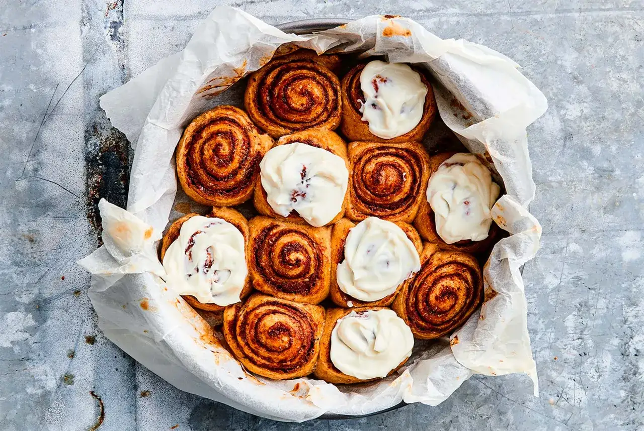 Nybakade kanelbullar med glasyr i en form. Dessa ägg i bulldeg ser ljuvliga ut!