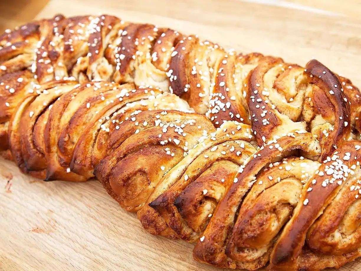 Två gyllene vetelängder, perfekt gräddade och strösslade med pärlsocker, ligger på en träskärbräda.