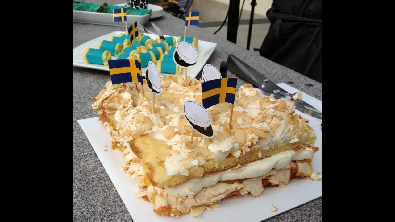 En gener&ouml;s pinocchiot&aring;rta med lemoncurd, toppad med mar&auml;ng och mandelsp&aring;n. Svenska flaggor och studentm&ouml;ssor pryder t&aring;rtan.