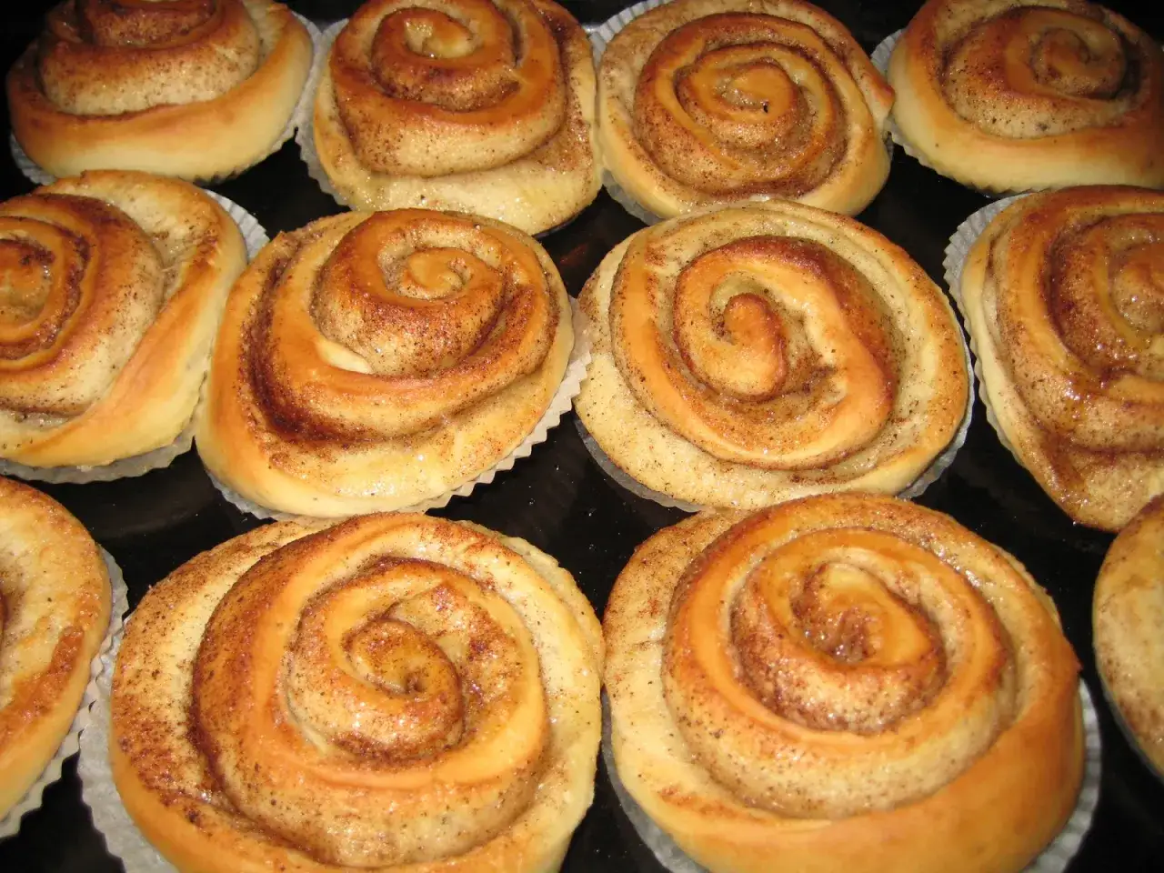 En närbild av gyllene kanelbullar utan ägg, perfekt bakade med en söt kanelfyllning och strösocker.
