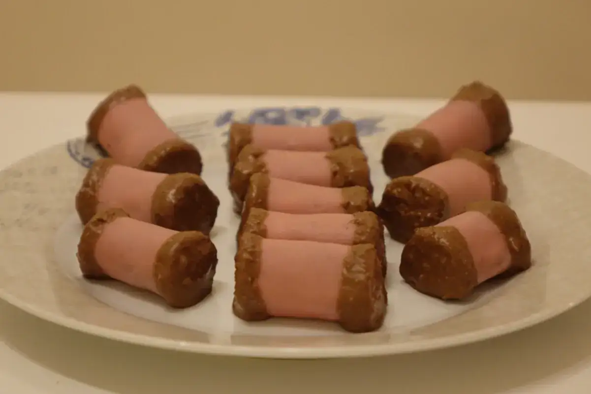 En tallrik med rosa punschrullar med chokladkanter. Perfekt för ett fika eller när du vill baka ett klassiskt punschrulle recept.