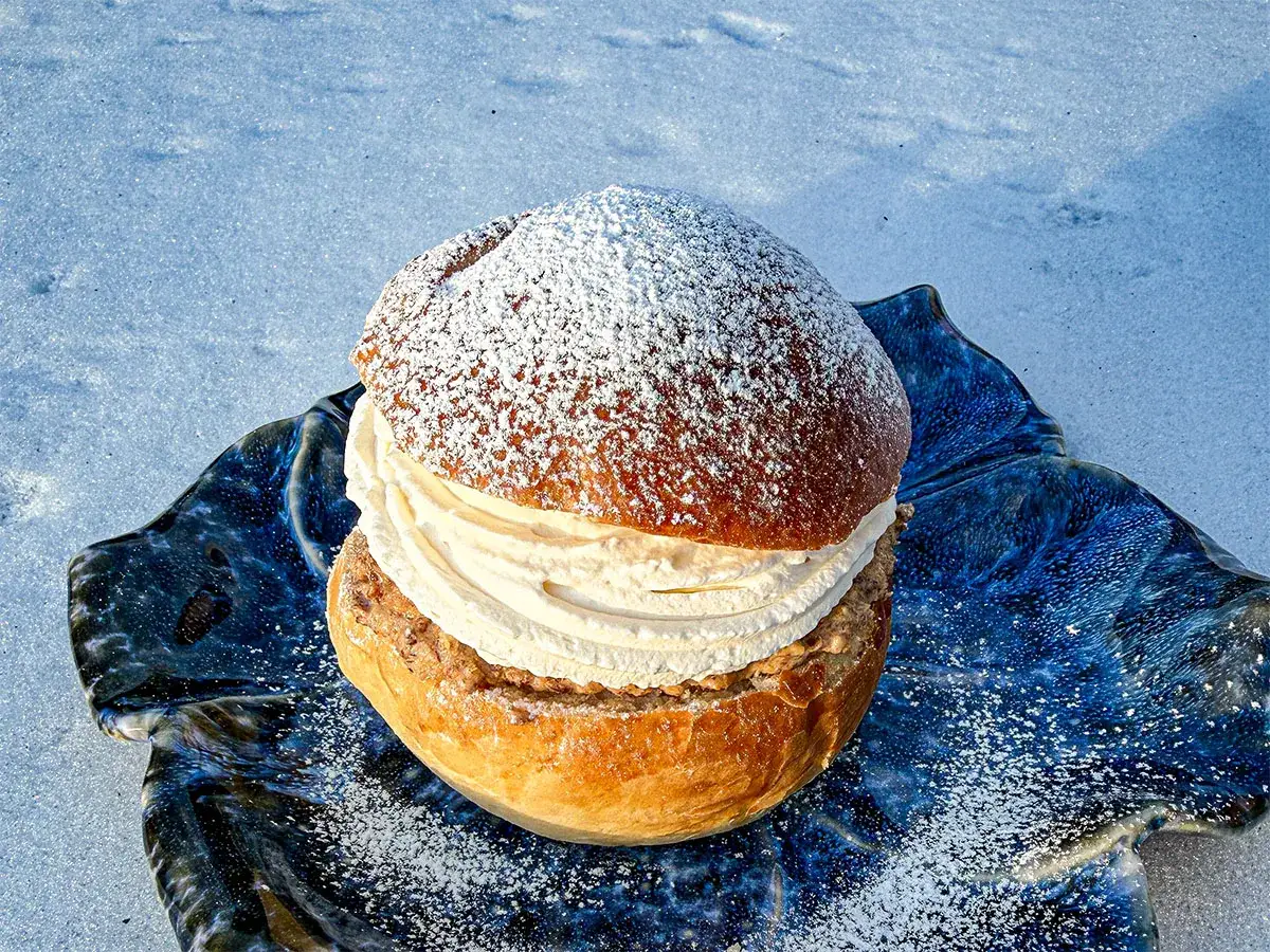 En härlig semla, perfekt för Fredriks fika, ligger på en blå keramikfat i snön.