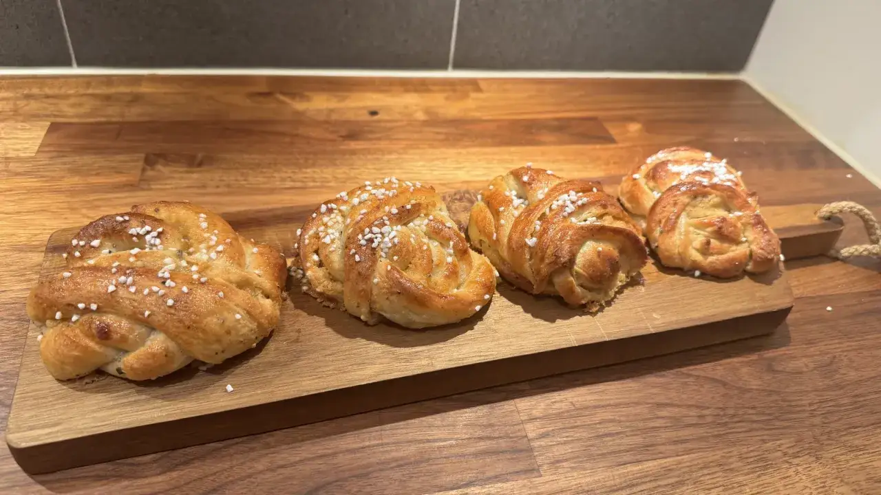 Färska, gyllene bullar, perfekt knyta bullar med pärlsocker på en träskärbräda.