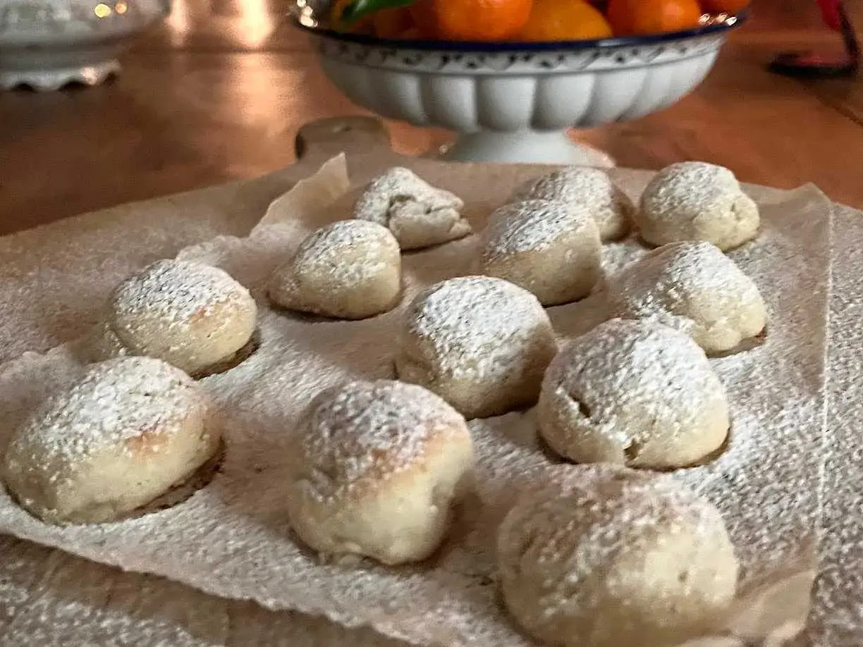 Små, pudrade bakverk som påminner om torta caprese, ligger på bakplåtspapper.